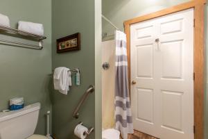 a bathroom with a toilet and a white door at The Barn Inn Bed and Breakfast in Millersburg