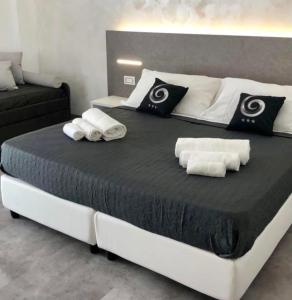 a large bed with black and white sheets and towels at Sesto Senso Home in Santa Maria del Cedro