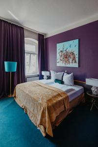 a bedroom with a large bed with purple walls at Boutique Hotel Rothenburger Hof in Dresden