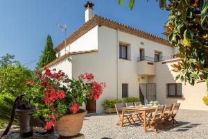 una casa con mesa, sillas y flores rojas en Can Cristus, en Monells