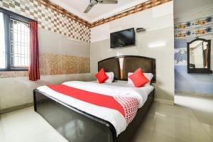 Schlafzimmer mit einem Bett mit roten Kissen und einem TV in der Unterkunft OYO Dkr Regency in Kurnool
