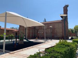 a playground with a white umbrella and a swing at La Casina del Cerecedo in León