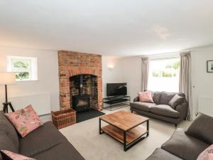 een woonkamer met een bank en een open haard bij Overton Cottage in Sturminster Newton