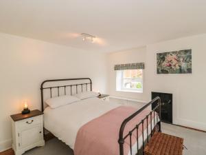 a white bedroom with a bed and a fireplace at Overton Cottage in Sturminster Newton