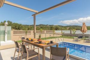 a patio with a table and chairs next to a swimming pool at Amelia Residence in Tragaki