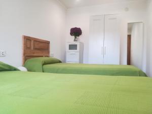 two beds in a room with green sheets at A Botica de Portomouro in Val do Dubra