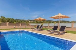 - une piscine avec 2 chaises longues et des parasols dans l'établissement Amelia Residence, à Tragaki