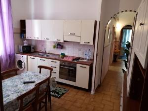 a kitchen with white cabinets and a table and a table and a tableablish at Grande Appartamento Dei Mille in Novi Ligure +12 photos