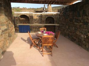 un patio con mesa, sillas y horno en Il dammuso di Giorgia en Pantelleria