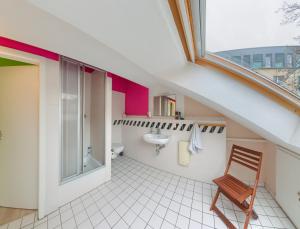 un bagno mansardato con lavandino e sedia di Labyrinth Hostel Weimar a Weimar Altre 37 foto