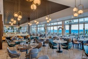 un restaurante con mesas, sillas y ventanas en Corendon Playa Kemer Hotel en Beldibi