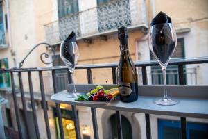 eine Flasche Wein und zwei Gläser auf dem Balkon in der Unterkunft Centro Storico Apartment in Procida