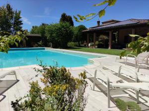 a swimming pool with white chairs next to a house at B&B Villa Valchero in Carpaneto Piacentino