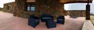 un patio con sillas y una pared de piedra. en Il dammuso di Giorgia en Pantelleria