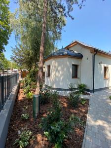 a small white building with a tree in a yard at Karinthy ház in Siófok