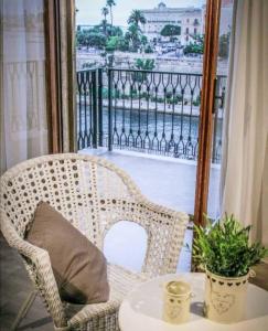 einen Korbstuhl auf einem Balkon mit einem Tisch in der Unterkunft Castello Aragonese Suites in Taranto