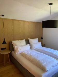 a bedroom with a large bed with white sheets and pillows at APART-MONTES in Sankt Ulrich am Pillersee