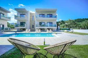 een villa met een zwembad en 2 stoelen bij Aquamarine Luxury Rooms Thassos in Limenas