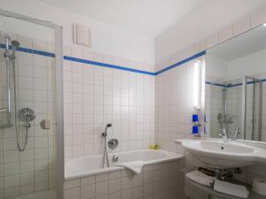 een badkamer met een bad, een wastafel en een douche bij Kaiservillen Heringsdorf - Ferienwohnung mit 1 Schlafzimmer und Terrasse D101 in Heringsdorf