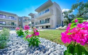 una casa con flores rosas delante de ella en Aquamarine Luxury Rooms Thassos, en Limenas