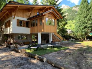 une maison dans les montagnes avec une terrasse dans l'établissement Dolomiti Chalet degli Abeti, à Campitello di Fassa