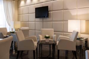 a waiting room with white chairs and a tv on a wall at Hotel Antico Borgo in Riva del Garda