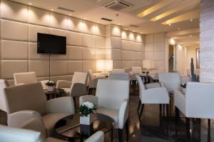 a room with white chairs and tables and a tv at Hotel Antico Borgo in Riva del Garda