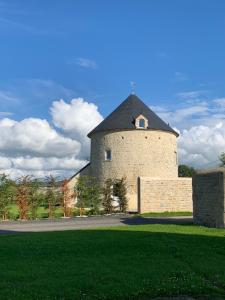 un grand bâtiment en briques avec une tour sur une pelouse dans l'établissement Gîte Manulau, à Turqueville