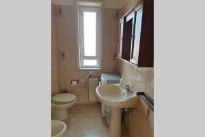 uma casa de banho com um lavatório, um WC e uma janela. em Casa vacanze Ada em Capo dʼOrlando