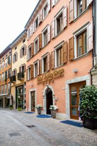 ein rosafarbenes Gebäude mit einem Schild auf einer Straße in der Unterkunft Hotel Antico Borgo in Riva del Garda
