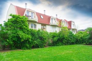 un bâtiment avec un toit rouge et des buissons verts dans l'établissement ILLÉS Apartmanok II., à Hajdúszoboszló