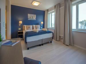 een slaapkamer met een bed en een blauwe muur bij Dünenresidenz Prora - Ferienwohnung mit Meerblick, 2 Schlafzimmern und Balkon NP-304 in Binz