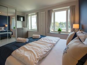 ein Schlafzimmer mit einem großen Bett, einem Sofa und Fenstern in der Unterkunft Dünenresidenz Prora - Ferienwohnung mit Meerblick, 1 Schlafzimmer und Balkon NP-310 in Binz