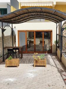 une terrasse avec une table et une arche en bois dans l'établissement Loft Ionios, à Noto Marina