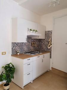 - une cuisine avec des placards blancs et une cuisinière dans l'établissement Loft Ionios, à Noto Marina