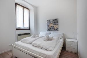 a white bedroom with a bed with white sheets at Casa Anna in Riva del Garda
