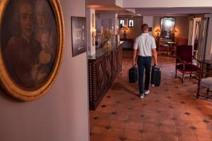 un hombre está caminando por un pasillo con equipaje en Hôtel Le Donjon - Cœur de La Cité Médiévale, en Carcassonne