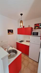 een keuken met rode kasten en een zilveren wastafel bij Vacation Home Licinius in Ližnjan