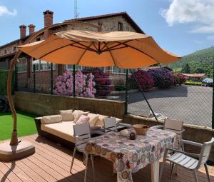 Vargas的住宿－Chalet Individual en Vargas, Cantabria，一个带桌子和遮阳伞的庭院