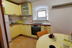 een kleine keuken met gele kasten en een tafel bij Apartment Veli Dvor in Cres