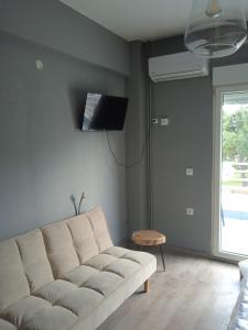 a living room with a white couch and a tv at Paralion Town Apartments in Alexandroupoli
