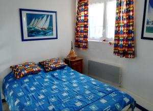 a bedroom with a blue bed with two pillows and a window at Maison cosy à La Tranche-sur-Mer - 45 m² avec jardin in La Tranche-sur-Mer