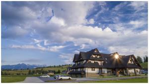 a large house with cars parked in front of it at Kaniówka Ski Resort- relaks w górach z basenem, sauną i jacuzzi in Białka Tatrzanska