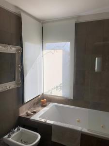 baño con bañera, lavabo y ventana en Haras Santa María en Matheu