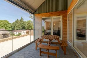 a patio with a table and benches on a balcony at Hill View Rise in Chipping Campden