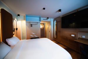 a bedroom with a large bed and a flat screen tv at You Hotels Deauville - Handwritten Collection in Deauville