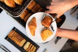 a person holding a plate of bread and pastries at You Hotels Deauville - Handwritten Collection in Deauville