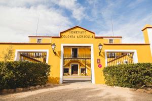 a yellow building with two garage doors in front at Hotel rural Entreviñas in Caudete de las Fuentes