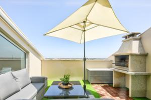a patio with a fireplace and an umbrella at Sea & River Vagueira Apartment by Home Sweet Home Aveiro in Praia da Vagueira