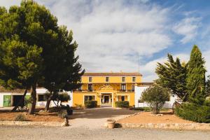 a yellow building with trees in front of it at Hotel rural Entreviñas in Caudete de las Fuentes